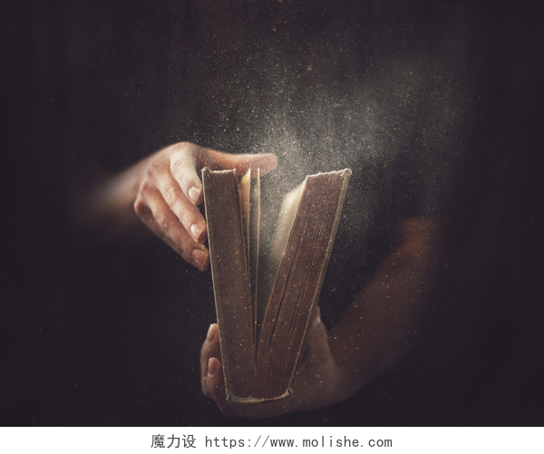 黑色背景中一只手正在打开一本书老满是灰尘的书